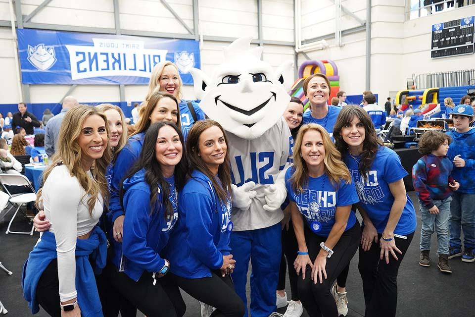 A group of women wearing 博彩网址大全 shirts pose for a photo with the Billiken.